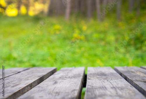 Empty wooden table surface against blurred mountain forest background with bright summer sunshine and copy space