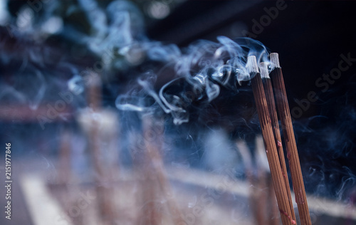 Fotografie Incense sticks burning with wisps of smoke rising in a serene outdoor setting, c
