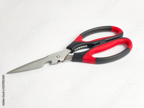 Multipurpose kitchen shears with sharp stainless steel blades, bottle opener feature, and ergonomic red and black handles, isolated on a white background.