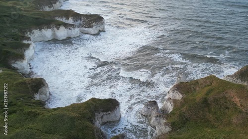 Drone aerial pull back shot of crashing ocean waves and white chalk cliffs Yorkshire