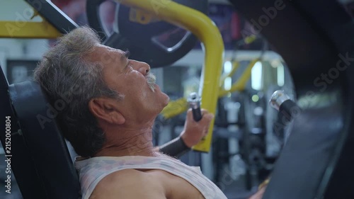 An Indian Asian fit healthy elderly or old man performs resistance or weight training exercise using a machine in a modern gym. Fitness, workout, healthy lifestyle, wellness. bodybuilding concept