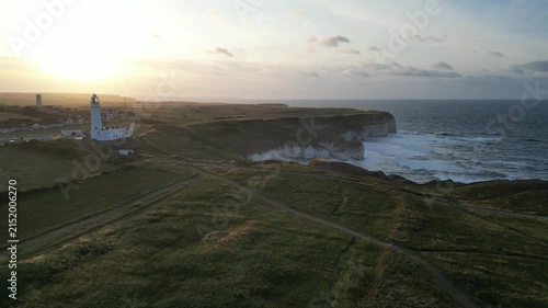 Wide aerial view of Flamborough Head Lighthouse and chalk cliffs at golden sunset, England
