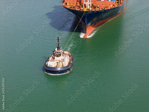 Small Tugboat Pulls a Large Cargo Ship Through the Ocean
