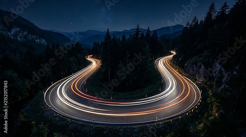 Cars driving on mountain road at night with long exposure light trails on hairpin curve