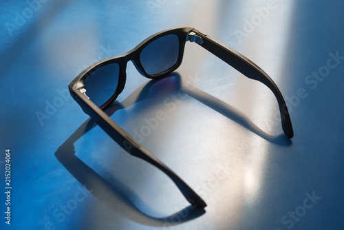Black modern smart glasses resting on a blue desk