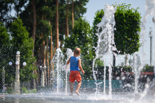 Happy Little Boys Playing in Splash Fountain on Hot Summer Day in City Park