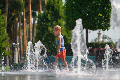 Happy Little Boys Playing in Splash Fountain on Hot Summer Day in City Park