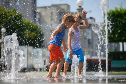 Happy Brothers Playing in Splash Fountain on Sunny Summer Day in City Park