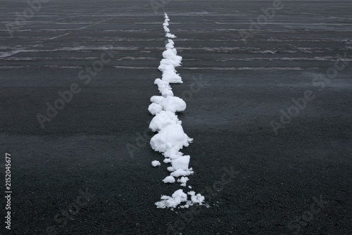 A line of snowy mounds stretches across a dark, textured surface