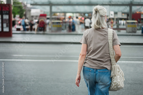 Caucasian senior woman walking at city bus station during evening time - Urban lifestyle concept - UGC content - Main focus on body