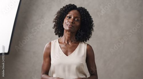 Portrait of a confident middle aged Black woman with curly hair looking at camera.