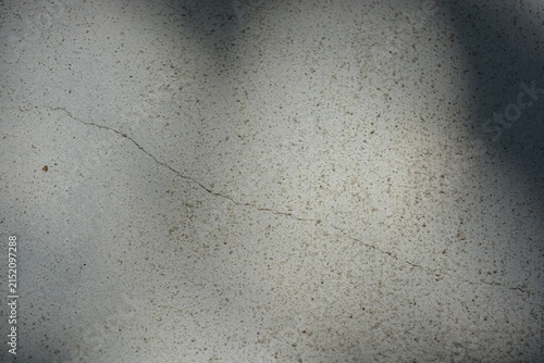 Construction and renovation work, plastering load-bearing street walls in sunlight. The white walls are coated with rough street primer with long micro-cracks throughout the surface and background.