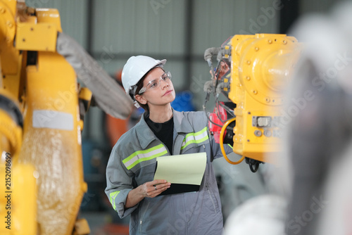 Photography Female engineer in hard hat inspecting complex machinery in a modern factory set