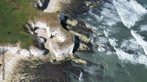 Aerial top down pull away view of ocean waves crashing on Flamborough cliffs, England