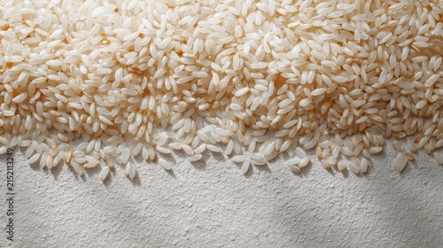 Close-up of uncooked, white rice grains spread over a textured surface with natural lighting and detailed focus