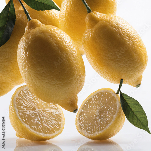 Fresh ripe lemons with green leaves and sliced halves isolated on a white background