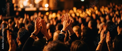 Audience Applauding at a Live Event with Blurred Lights in the Background.