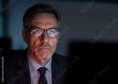 A middle-aged respectable man wearing glasses watches the monitor, the work of a trader, an editor.
