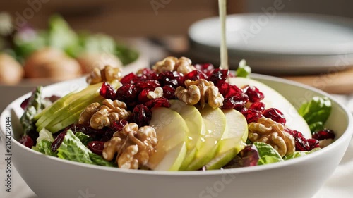 Fresh green salad with sliced apples and walnuts being dressed
