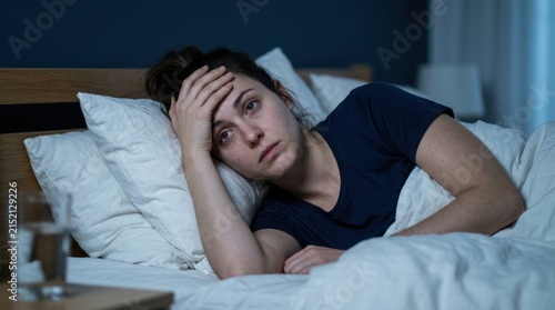 Stressed woman suffering from insomnia lying awake in bed at night