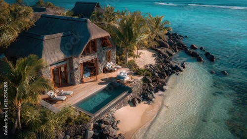 Tropical beach resort with thatched roof buildings, pool, and turquoise water