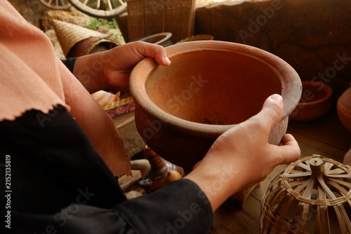 Close-up of tourist hands holding handmade earthenware vessel at local craft shop
