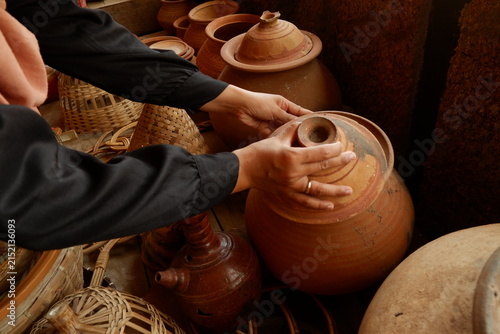 Customer examining brown terracotta pot at traditional artisan pottery store