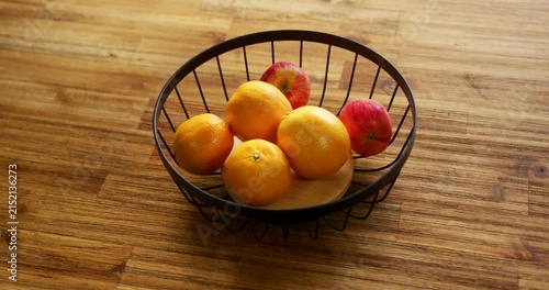 Camera is slowly tightening composition, bringing wire fruit basket closer on countertop, centering