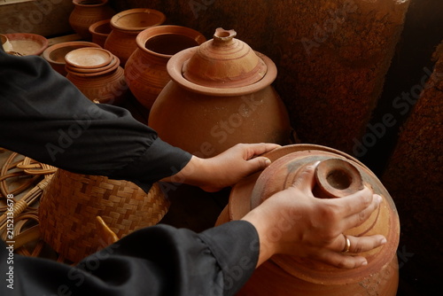 Close-up of tourist hands holding and inspecting handcrafted ceramic earthenware vessel