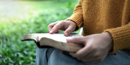 Fotografie A young woman is reading an open Bible outdoors, praying for peaceful healing in nature and the Holy Word