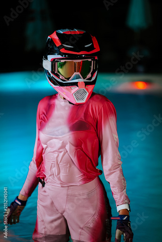 Konstfotografi Motocross rider in pink racing gear standing inside a blue illuminated swimming