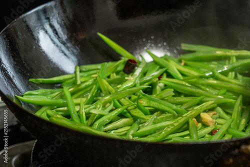 Fotografie Stir-frying sliced green beans with dried chilies and garlic in a carbon steel w
