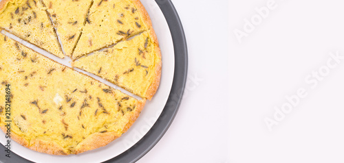 Piatto con fette di frittata alle erbe aromatiche, vista da sopra su una superficie bianca con spazio per testo