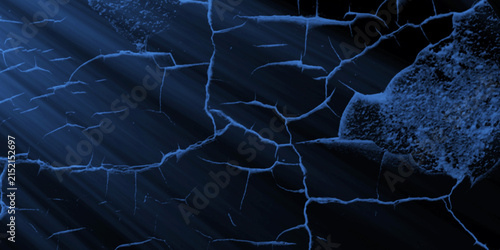 Blue light rays illuminate a cracked blue surface texture creating a dramatic effect