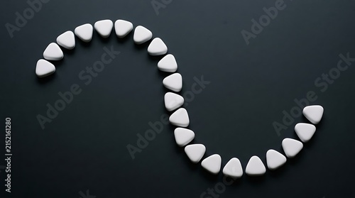 Arrangement of polished white magnesite stones forming a curved line on a dark surface