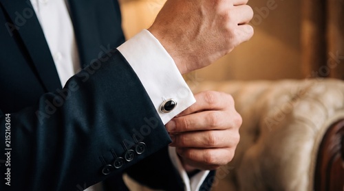 Elegant man adjusting cufflink on formal shirt sleeve in luxury setting
