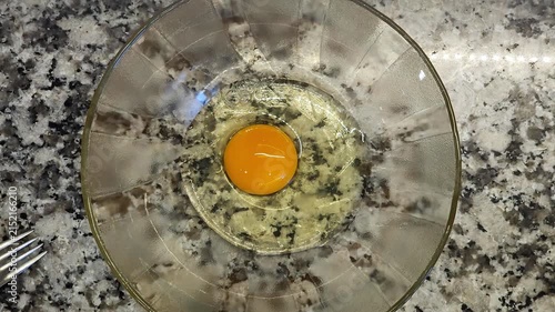 Manos rompiendo huevos crudos dentro de un cuenco transparente