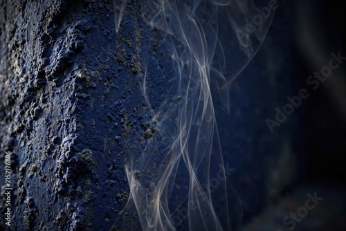 Abstract Dark Blue Smoke Swirls Against Textured Surface.