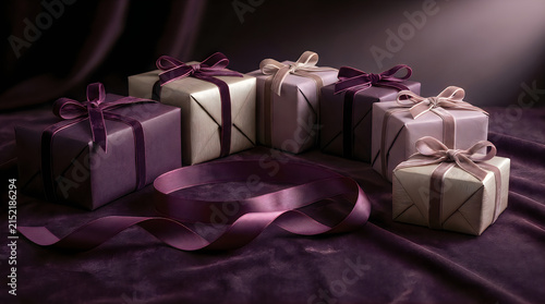 Elegant gift boxes wrapped in luxurious purple and beige paper tied with satin ribbons