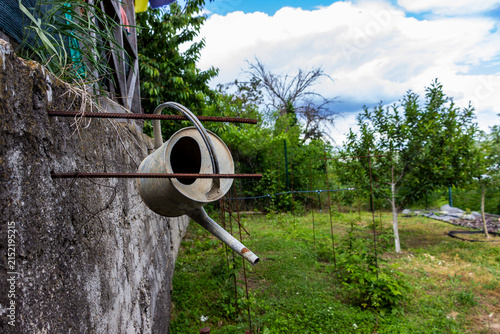 Fotografie old garden watering can hanging on the fence in the garden, countryside, rarity,