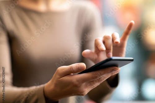 Point finger on screen mobile phone closeup. Hand using smartphone at room blur bokeh background. Searching data networks or chatting online. Typing sending message. Mockup smart phone wireless.