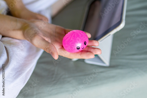 Teenager stretches a pink squishy toy while watching a tablet in bed. Flexible tactile play combines sensory exploration, digital entertainment and relaxation in everyday life