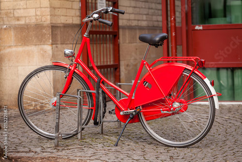 Red Vintage City Bicycle Parked on Cobblestone Street. Urban Eco-Friendly Sustainable Transportation. Vintage Style Urban Cycling Transportation