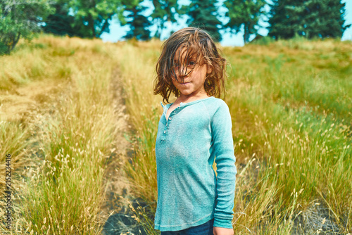 фотографія Boy with windswept hair standing on a hillside path facing the camera
