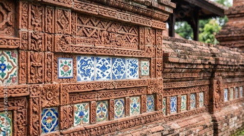 Ancient terracotta brick wall with ornamental ceramic tile details, terracotta