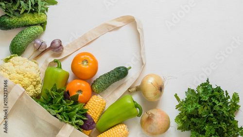 Fresh assorted vegetables and herbs arranged with a reusable canvas shopping bag, promoting healthy eating, groceries, and sustainable food choices. Copy space.