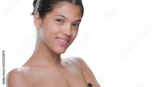 Close shot of beauty model strokes her shoulder standing behind a wet glass showing hydrated skin isolated on white | Body wash commercial footage