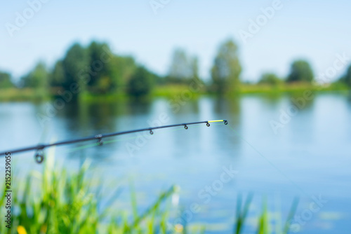 Картината върху платно Fishing feeder rod tip over calm lake water with blurred natural landscape background