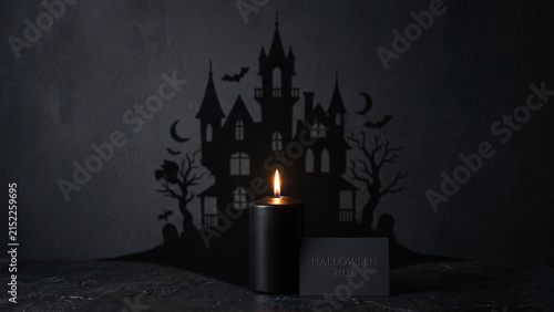 Spooky Halloween celebration with burning black candle and haunted house silhouette