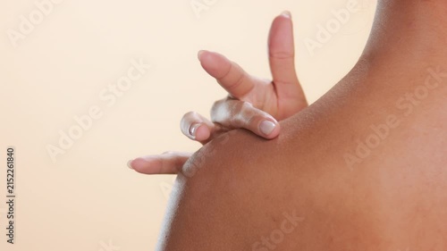 Choker closeup of young model standing back to camera and stroking her shoulder highlighting moisturized skin on neutral background | Cosmetic video for moisturizer advertisement